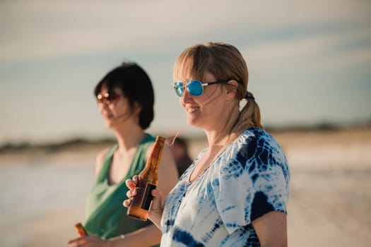 Mature adult and her female friend relaxing with a bottle of beer on a beach in Perth, Australia.