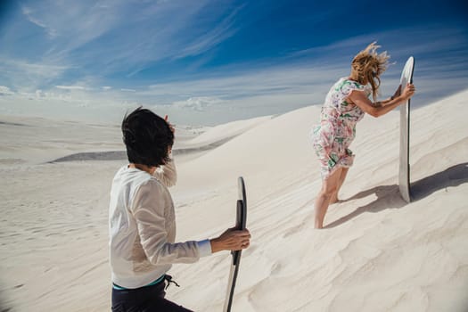 Side view of two female friends walking up a sand dune at Lancelin sand dunes, Perth, Australia.