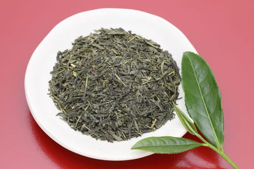 Dried tea leaves with green tea leaves on red background