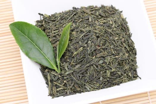 Dried tea leaves with green tea leaves on bamboo background