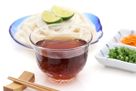 Japanese chilled udon noodles in a glass plate with soy sauce on white background