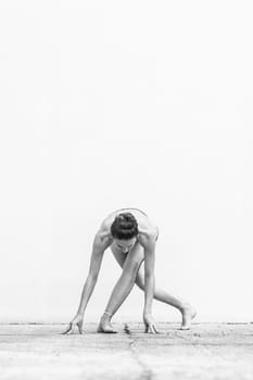 Fit sporty active girl in fashion sportswear doing yoga fitness exercise in front of gray wall, outdoor sports, urban style. Black and white image.