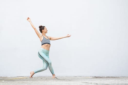 Fit sporty active girl in fashion sportswear doing yoga fitness exercise in front of gray wall, outdoor sports, urban style.