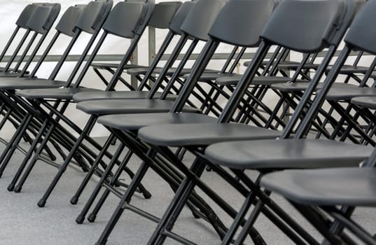 numerous folding chairs arranged in a row in a conference room.
