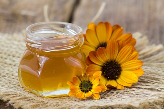honey and flowers on wooden background