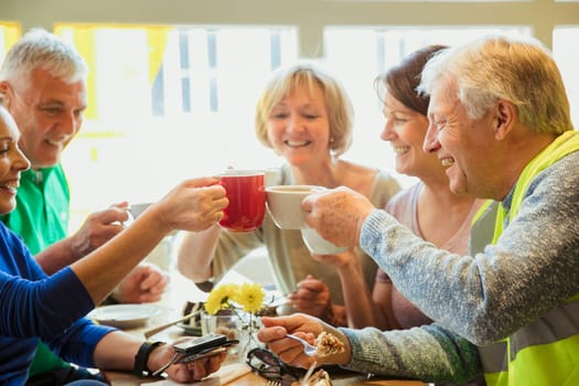 A group of five people taking a break from city cleaning and toasting with their coffees.