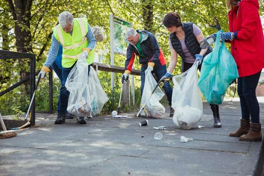 A group of five people participating in a city clean-up together.