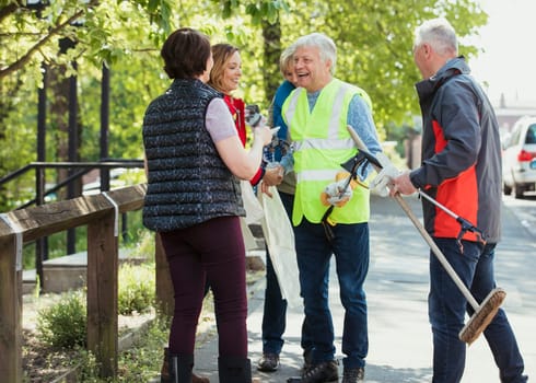 A group of city cleaners talking outdoors, participating in a city clean up.