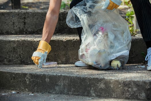 A close-up of an unrecognizable person picking up litter on the streets.