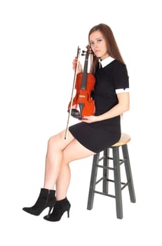 A beautiful woman sitting in a black dress holding her violin resting.looking into the camera, isolated for white background.