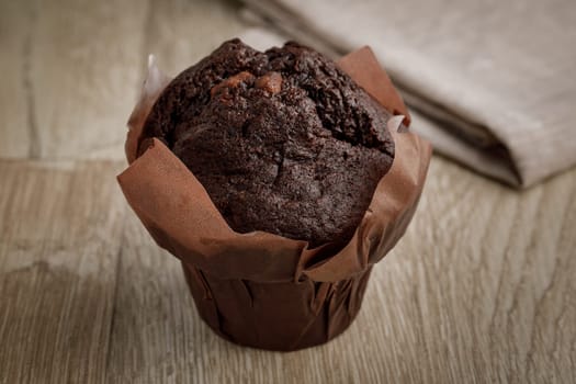 Chocolate cake in baking paper on a wooden surface