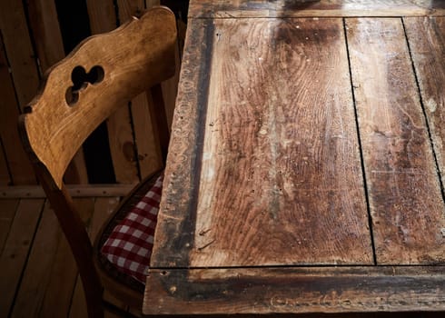 Bare rustic or vintage old wooden table and chair lit by daylight from a window for product or food placement