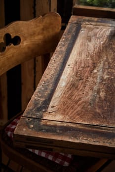 Partial view of a bare old rustic wood table and chair with copy space for placement of food or products in a vertical view