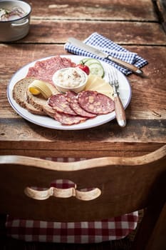 Tasty lunch platter with cheese and dried and cured wild venison sausage, rye bread and a creamy dip or spread on an old rustic table