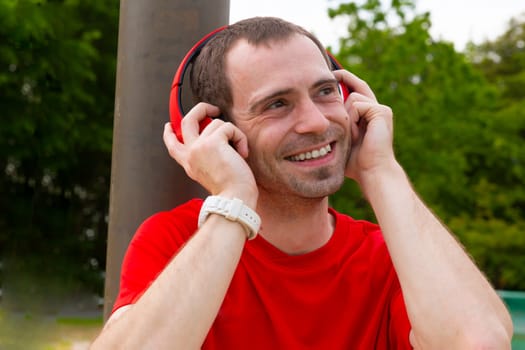 Young joyful Sportsman with red headphones in nature