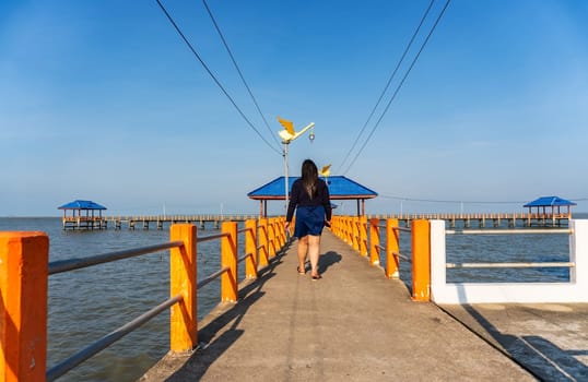 Some people walking on the bridge in the blue sea in evening light