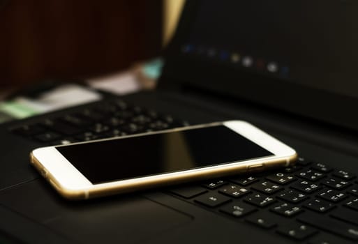 Social network and internet connection concept, Smart phone mobile on computer keyboard with copy space dark filter background