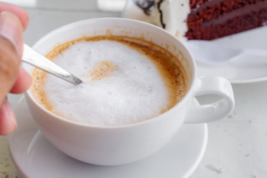Latte coffee in a white cup on white table blurred background