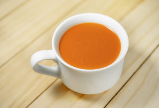 Hot milk tea in a white cup on wooden background