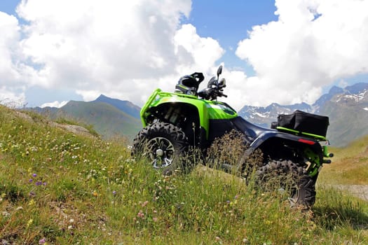 With the ATV in the mountains. A green ATV stands on a steep mountain path.