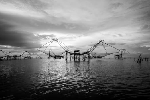Black and white photo landscapes of Songkhla Lake at sunrise and fishing square dip net is a local fishing tool rural lifestyle at Pakpra canal, Baan Pak Pra, landmark of Phatthalung in Thailand