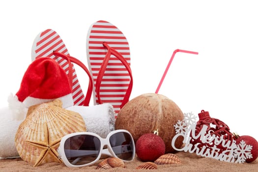 Still life with beach accessories (flip flops, towel, seashells, sand, coconut) and christmas ornaments on white background. Christmas. Winter vacation in warm countries, beach holiday