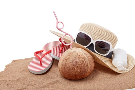 Beach accessories: flip flops, straw hat, sunglasses, sunscreen and coconut, lying on the sand on white background. Concept of sea vacation and travel. Summer background, Protection from uv