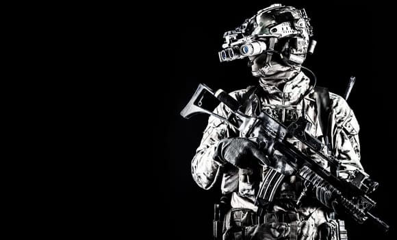 Half length portrait of army special forces rifleman, commando elite soldier equipped radio tactical headset, armed service rifle, using night vision goggles in darkness, isolated on black, copyspace