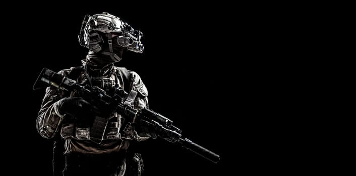 Modern army special forces equipped soldier, anti terrorist squad fighter, elite mercenary armed assault rifle, standing in darkness with night vision goggles on helmet, studio portrait, copyspace