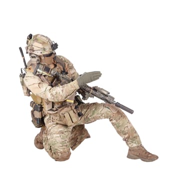 Special forces sergeant, battle squad leader in camo uniform, helmet with radio headset, armed rifle standing on knee, pointing direction, giving orders to teammates studio shoot isolated on white