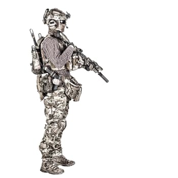Full length portrait of airsoft player in checkered shirt, wearing camouflage uniform, helmet with tactical radio headset, body armour, aiming with service rifle replica studio shoot isolated on white