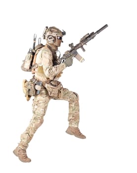 Army soldier, equipped infantryman, airsoft player in camouflage battle uniform, helmet and tactical radio headset jumping, running with assault rifle in hand studio shoot isolated on white background