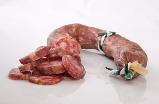 Cured spicy sausage with some cut pieces. Isolated over with background
