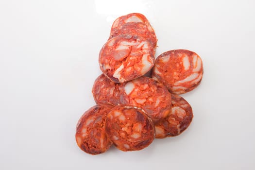 Some cut pieces of red iberian chorizo. Isolated over white background