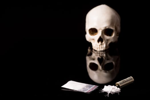 cocaine, Herion or other illegal drugs that are sniffed by means of a tube or injected with a syringe, money and Skull, isolated on black glossy background