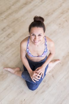 Cheerful fit sporty active girl in fashion sportswear sitting on the floor in yoga studio. Active urban lifestyle.