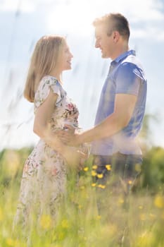 Young happy pregnant couple hugging in nature. Concept of love, relationship, care, marriage, family creation, pregnancy, parenting