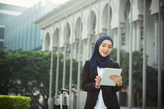 Muslim woman working on table pc outdoor, business travel concept.