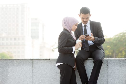 Business people using smartphone outside office.