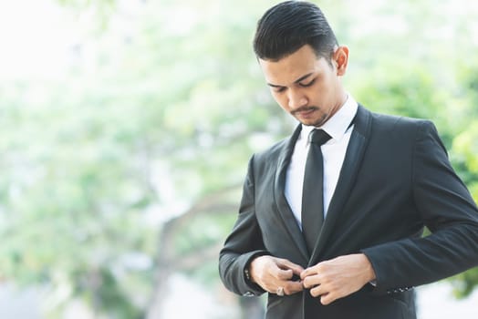 Asian businessman button his suit, get ready for work.
