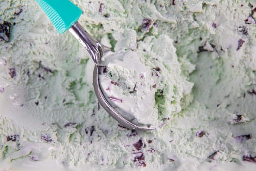 Top view of mint flavour ice cream with chocolate flakes in box. Focus on ice cream in scoop.