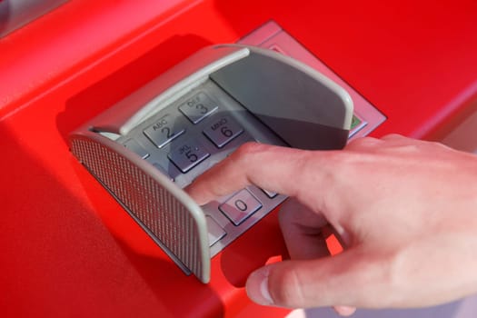 close up of hand entering pin code at cash machine