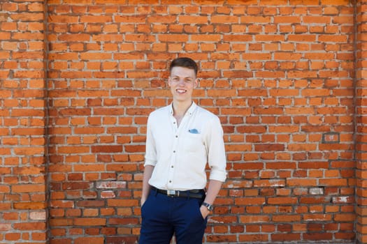 Portrait of a casually dressed young businessman standing against a brick wall