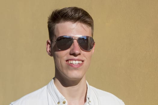 portrait of a handsome man dressed in white shirt against yellow wall