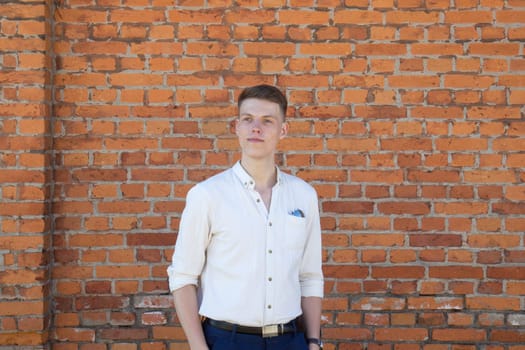 Portrait of a casually dressed young businessman standing against a brick wall