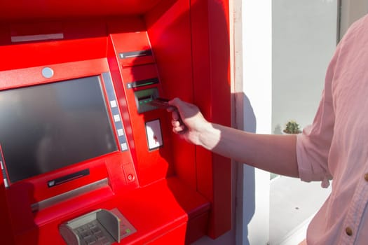 Hand of a man with a credit card, using an ATM. Man using an atm machine with his credit card.