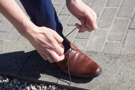 Man tying shoes laces on the street