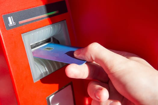 Hand of a man with a credit card, using an ATM. Man using an atm machine with his credit card.