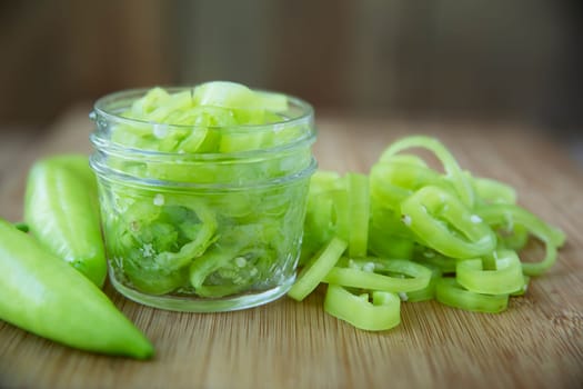 Fresh sliced banana peppers on a cutting board with jar ready for pickling.