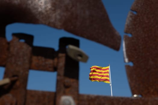 Closeup of blurred weather vane with padlocks and the Catalan flag focused in the background. Concepts of closure and frustration.
